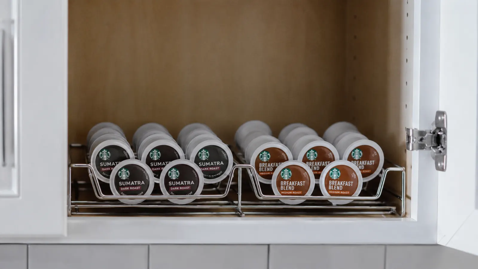 Organized small cabinet shelf holding a neat row of K-Cup coffee pods sorted by roast level